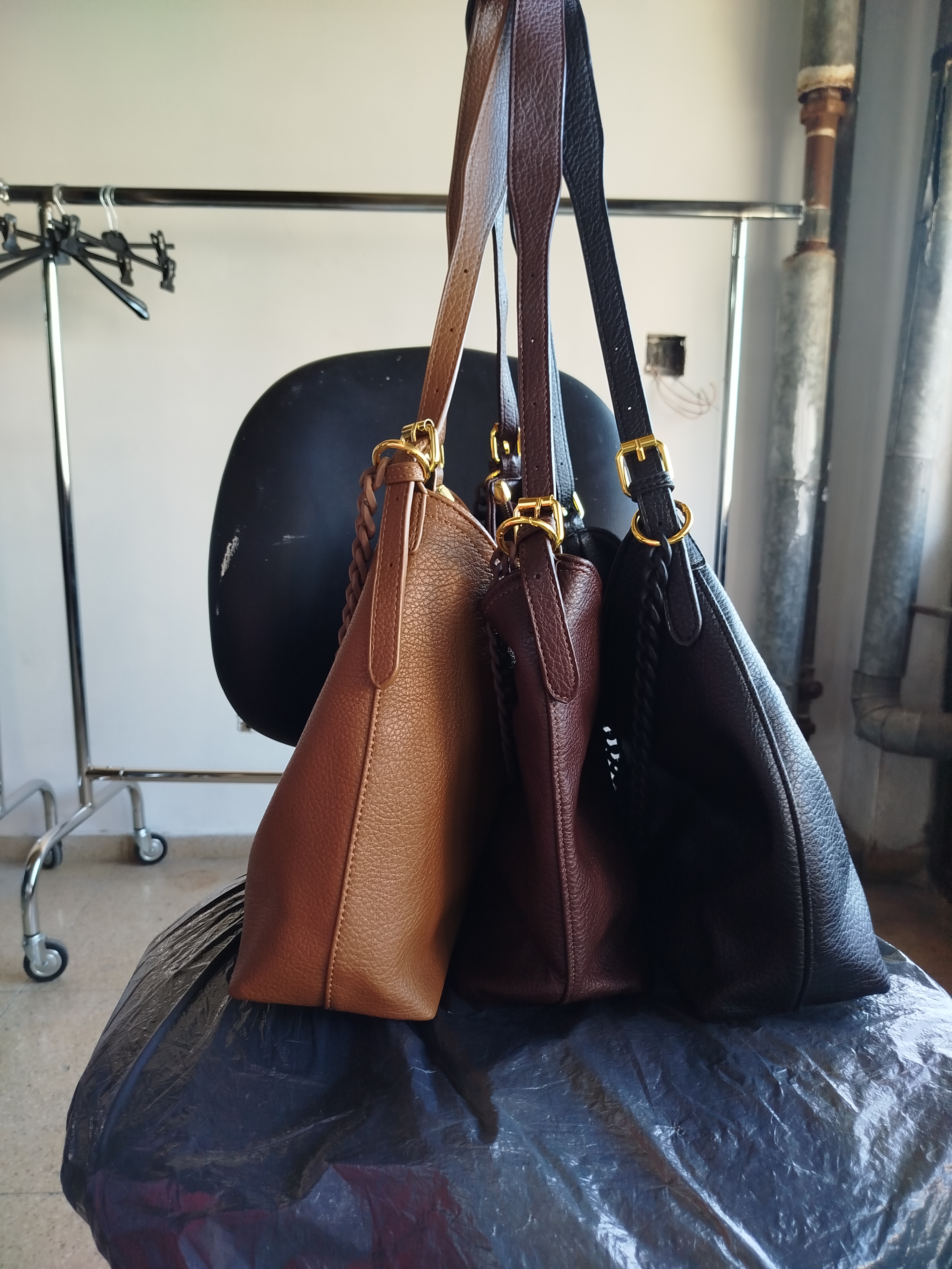Trío de bolsos crossbody de cuero colgados en el perchero del taller