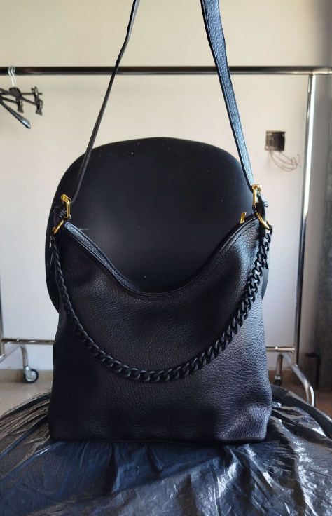 Bolso de cuero negro colgado en un perchero del taller