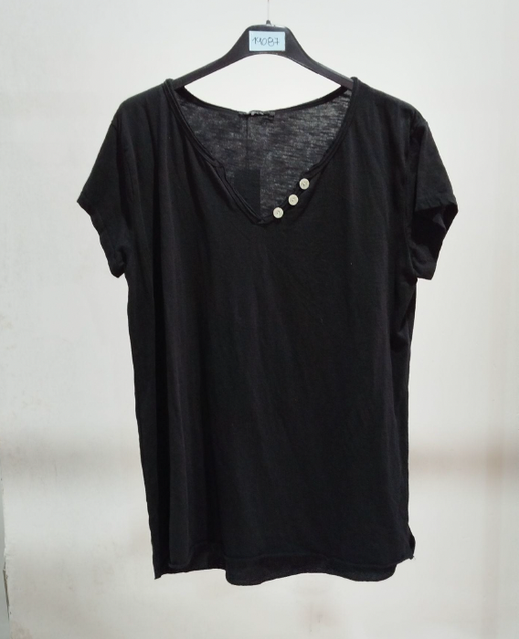 Remera de lino fotografiada en percha contra una pared